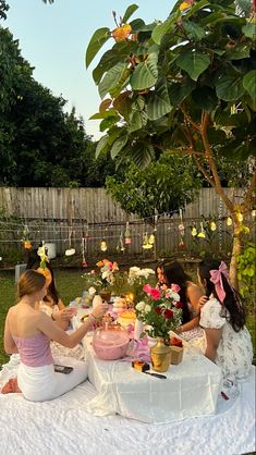 several women sitting around a table with cake on it