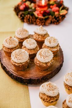 cupcakes with white frosting sitting on top of a wooden board next to other dessert items