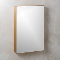 a mirror mounted to the side of a wall next to a white wall with a gold frame