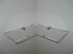 the corner of a white wall with two glass shelves