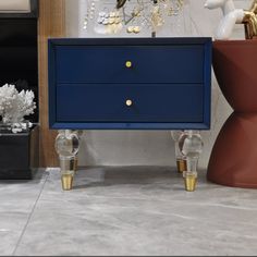 a blue dresser with two gold handles and some glass vases on the floor next to it