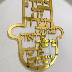 a gold metal wall hanging with the word hamsa written in different languages on it