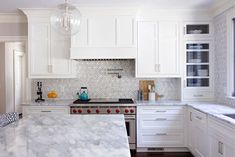 a kitchen with white cabinets and marble counter tops