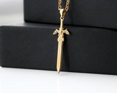 Master sword necklace in the style of the famous attribute from The Legend of Zelda is made of 925 sterling silver and 24k gold plated. For fans of The Legend of Zelda video game, this necklace will be a stylish and original accessory. You can choose the options of the chain on which the pendant will be placed: it can be a classic chain made of 925 sterling silver or a textile cord with a 925 sterling silver lock. The pendant has a hidden eyelet for the chain, which makes it look unsurpassed . I Tears Of The Kingdom Cosplay, Loz Merch, Zelda Jewelry, Link Earrings Zelda, Legend Of Zelda Necklace, Zelda Gifts, The Witcher Swords Silver, Tears Of The Kingdom, Gothic Pendant