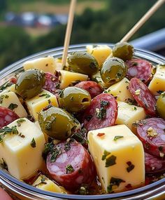 a bowl filled with olives, cheese and pickles on top of a table