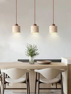 a dining room table with four chairs and three lights hanging from it's ceiling