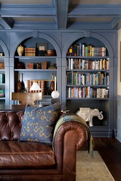 a leather couch sitting in front of a book shelf filled with books