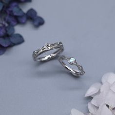 two silver rings sitting next to each other on top of a blue table with flowers