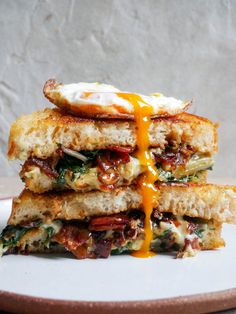 three grilled sandwiches stacked on top of each other with an egg being drizzled over them