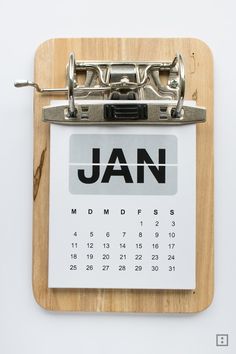 a calendar on a wooden clipboard with the word jan written in black and white