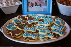 a plate full of dog paw cookies next to a baby's frame and bowl of candies