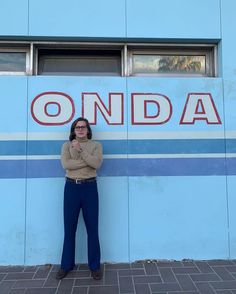 a woman standing in front of a blue wall with the word onda painted on it