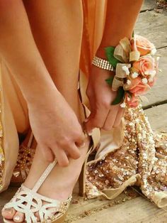 a woman in high heels tying her wedding shoes with flowers on the toe and side