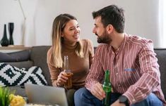 a man and woman sitting on a couch with beer