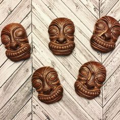 four carved wooden masks sitting on top of a wood floor