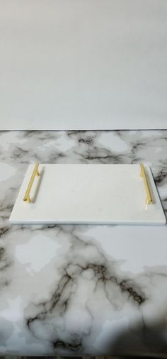 a marble counter top with gold handles and a white tray on it that has a golden handle