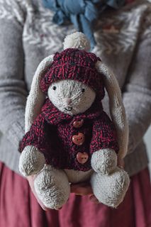 a woman is holding a stuffed animal in her hands while wearing a red dress and hat