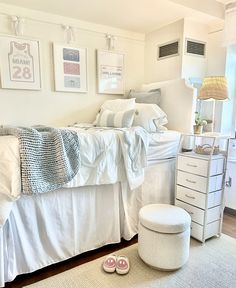 a bedroom with white furniture and pictures on the wall above the bed, along with a pair of pink slippers