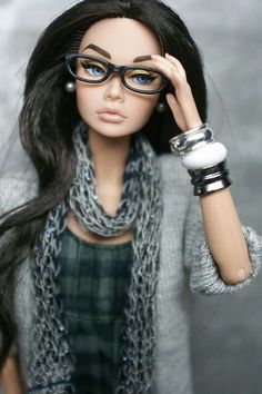 a doll with glasses and a scarf around her neck is holding her hand up to her face