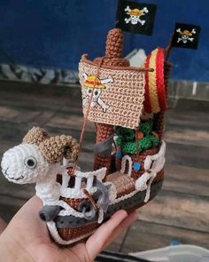 a hand holding a small crocheted pirate ship