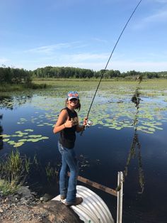 a woman standing on top of a boat holding a fishing pole