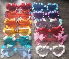 six pairs of butterfly shaped sunglasses with beads and bows on the sides, all in different colors