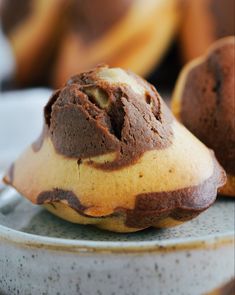 two chocolate muffins on a plate with bananas in the backgroung