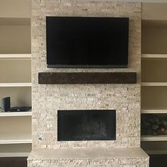 a tv mounted above a fireplace in a living room with built - in shelving