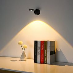 a lamp that is on top of a shelf next to some books and a vase with flowers