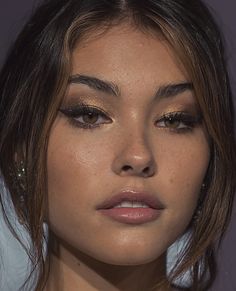 a close up of a woman with brown eyeshadow and gold eyeliners