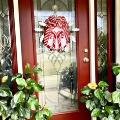 the front door is decorated with red and white candy canes, greenery, and a wreath