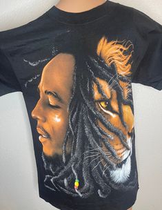 Zion Rootswear brand (Marley Co.), black t shirt with Bob Marley and Lion face printed on the front. Size small. %100 cotton, made in USA. Vintage but new! Never worn, not preowned. New/old store inventory. Casual Black T-shirt With Custom Artwork, Black Cotton Tops With Custom Artwork, Black Tops With Custom Artwork For Streetwear, Black Custom Artwork T-shirt For Streetwear, Black Band Merch T-shirt With Custom Artwork, Black T-shirt With Custom Artwork For Streetwear, Black Crew Neck T-shirt With Custom Artwork, Black Graphic Tee With Custom Artwork, Bob Marley Lion