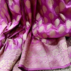 This stunning pink 100% Mulberry Katan silk saree is handwoven in Banaras, known for its intricate designs and high-quality craftsmanship. The saree features a beautiful shade of dual - pinkish purple with golden zari jaal work, creating a mesmerizing effect. The saree is perfect for any special occasion, such as a wedding, festival, or formal event. Comes finished with hand fall and Pico. And a blouse piece with zari border. Silk Mark Certified Note: Colors that show up on your screen may vary slightly from the actual product due to variations in settings. Also, the actual product may appear to be different hues depending on the ambience lighting.Note: There may be very slight inconsistencies such as in the weave/motiff work or color , there being characteristics are not considered defect Purple Slub Silk Saree For Puja, Festive Purple Slub Silk Traditional Wear, Purple Chanderi Lehenga For Puja, Unstitched Purple Saree For Celebration, Purple Slub Silk Traditional Wear For Wedding, Pink Anarkali Blouse In Slub Silk, Pink Anarkali Blouse Piece In Slub Silk, Pink Slub Silk Traditional Wear For Diwali, Diwali Pink Slub Silk Traditional Wear