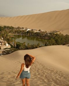 a woman in shorts is walking through the sand dunes