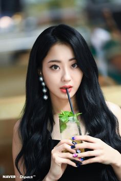 a woman with long black hair holding a drink