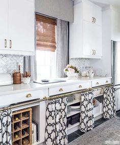 a kitchen with white cabinets and black and white curtains