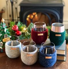 four wine glasses sitting on top of a table next to a christmas tree and fireplace