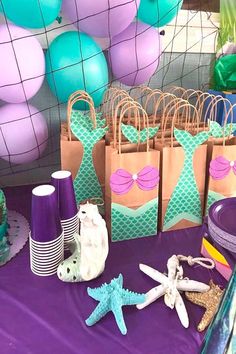 there are many bags and starfish on the table with purple, blue and green decorations