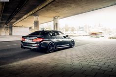 a black car is driving under a bridge