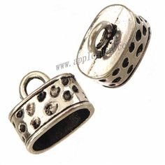 two silver colored charms with black dots on the bottom and one has a hole in the middle