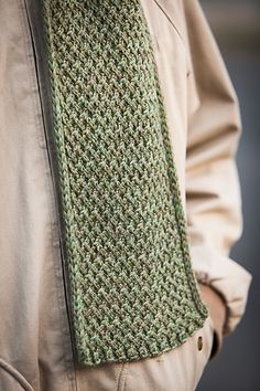 a close up of a person wearing a green knitted necktie and tan jacket