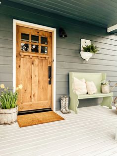 a wooden door sitting on the side of a house next to a bench and potted plant