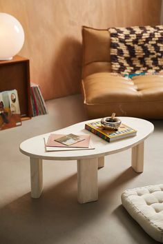 a living room with a couch, coffee table and books on the floor in front of it