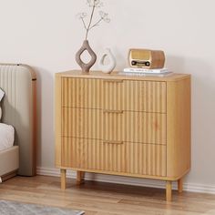 a wooden dresser sitting next to a bed in a room with white walls and wood flooring