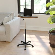 a laptop computer sitting on top of a wooden table next to a white couch in a living room