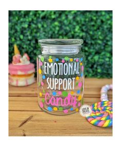 a jar filled with candy sitting on top of a wooden table next to a cookie