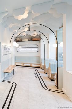 the interior of a restaurant with white walls and black lines on the floor, along with wooden benches