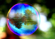 a soap bubble with the words bouncing bubbles on it in front of trees and water