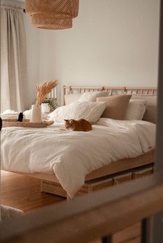 a cat laying on top of a bed in a room with white walls and wooden floors