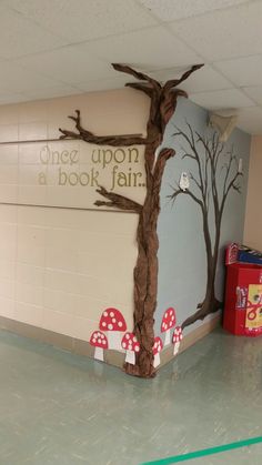 there is a tree painted on the wall in this school hallway with mushrooms and trees